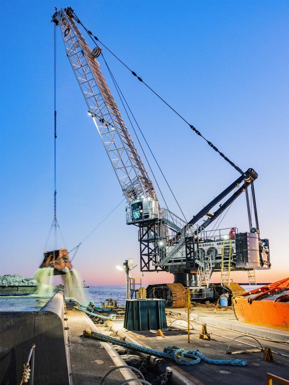 Dutra Group and Matthews Brothers, Inc. operate the HS 8300 duty cycle crawler crane in Port Arthur, Tx in the Gulf of Mexico at sunset.