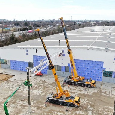 Prillaman Crane and Rigging utilizing a yellow Liebherr LTM 1090-4.2 mobile crane and a LTM 1250-5.1 mobile crane to complete a safe demolition at the back of the Liebherr Mining Newport News campus.